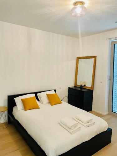 - une chambre avec un grand lit blanc et des oreillers jaunes dans l'établissement New & Large 1 bedroom in Center- terrace & parking, à Luxembourg