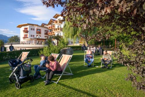 a group of people sitting in chairs on the grass at La Montanina Hotel in Val di Non in Malosco