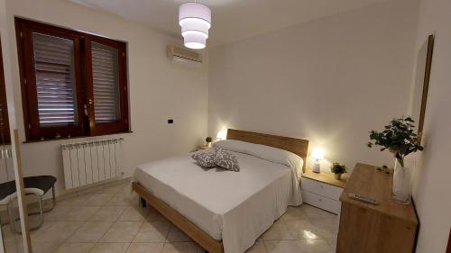 a white bedroom with a bed and a window at A me Casa in Gioiosa Marea