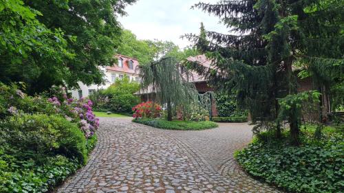 a brick walkway with flowers and trees and a building at 4 Sterne-Haus am See in Waren