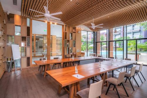 a restaurant with wooden tables and chairs and windows at Holiday Inn Express Phuket Patong Beach Central by IHG in Patong Beach