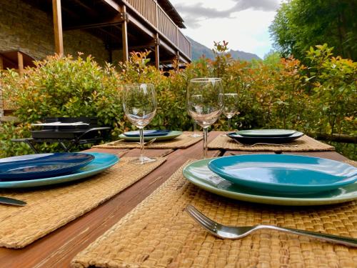 a wooden table with plates and wine glasses on it at Chalet Casa La Cumbrecita en Panticosa in Panticosa