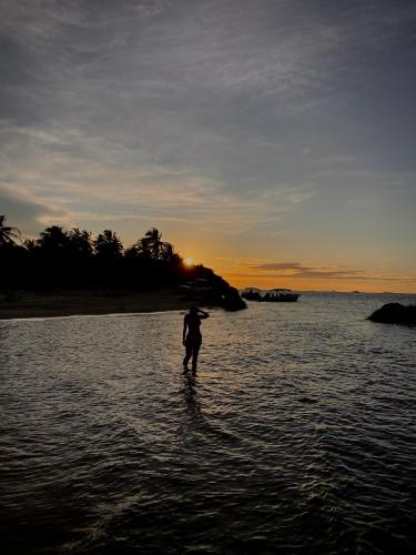 a person standing in the water at sunset at Oka Pousada Atins in Atins