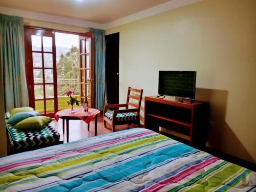 a bedroom with a bed and a tv and a window at Fundo San Silvestre in Huaraz