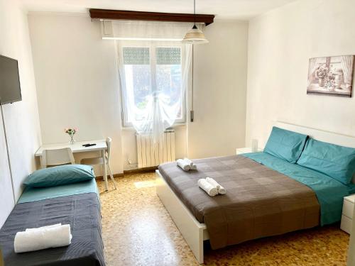 a bedroom with two beds and a desk and a window at PORTA A MARE STATION in Pisa