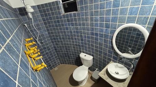 a blue tiled bathroom with a toilet and a mirror at Oka Pousada Atins in Atins