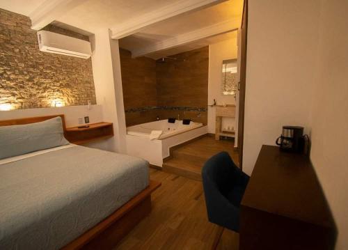 a bedroom with a bed and a bathroom with a tub at El Jardín de la Abuela in Querétaro