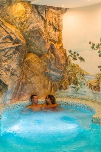 a painting of two people in a swimming pool at La Montanina Hotel in Val di Non in Malosco