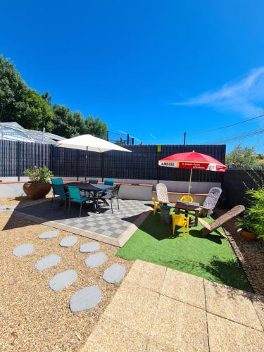 een patio met een tafel en stoelen en een parasol bij La Gelotière propose 2 logements indépendants à 10 min du Puy du Fou in Sevremont