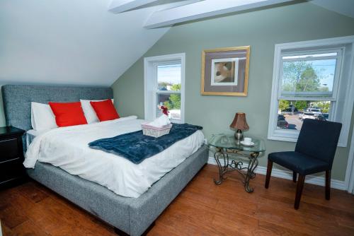 a bedroom with a bed and a table and a chair at Cute 2-story, 2-bdrm Loft, Mins to Beach and Lake in Cobourg
