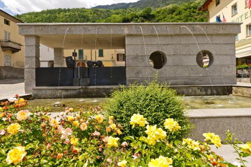 a garden with flowers in front of a building at Hotel Garni Le Corti in Grosotto