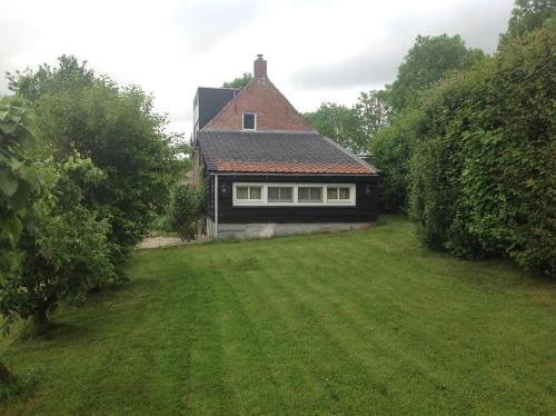 a house with a grass yard in front of it at Dijkhuisje Zeeland in Waterlandkerkje