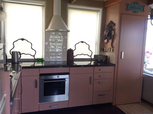 a kitchen with a stove top oven next to two windows at Dijkhuisje Zeeland in Waterlandkerkje