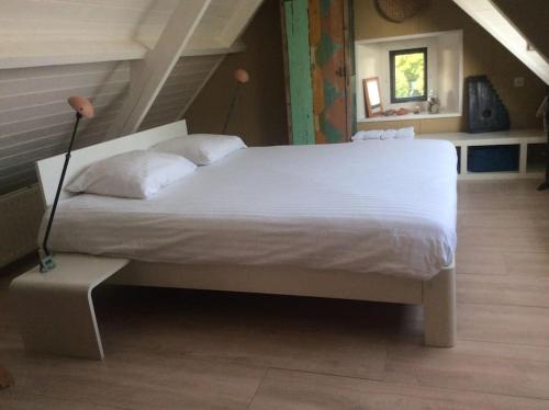 a bedroom with a large white bed in a attic at Dijkhuisje Zeeland in Waterlandkerkje