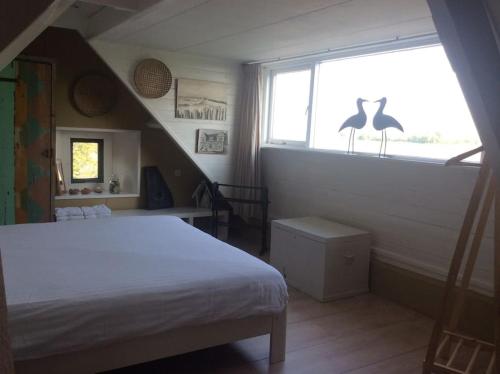 a bedroom with a bed and a window with a bird statue at Dijkhuisje Zeeland in Waterlandkerkje