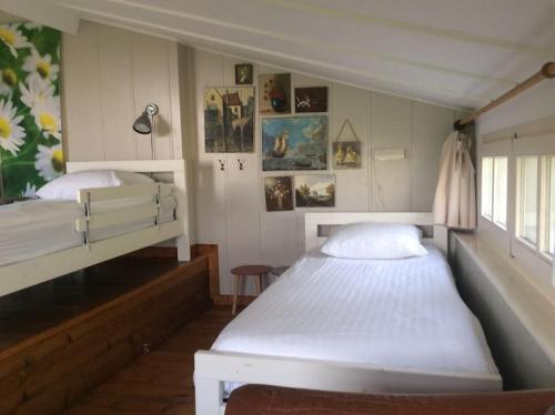a bedroom with two beds and pictures on the wall at Dijkhuisje Zeeland in Waterlandkerkje