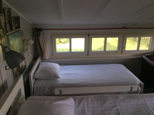 two beds in a small room with two windows at Dijkhuisje Zeeland in Waterlandkerkje