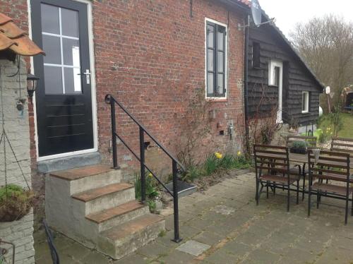 a brick house with a staircase and a table and bench at Dijkhuisje Zeeland in Waterlandkerkje