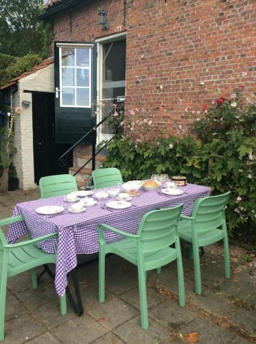 a table with a purple table cloth and green chairs at Dijkhuisje Zeeland in Waterlandkerkje