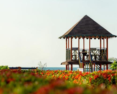 a gazebo on the beach with flowers at Hotel Agroturistico Palma Vino in Arboletes