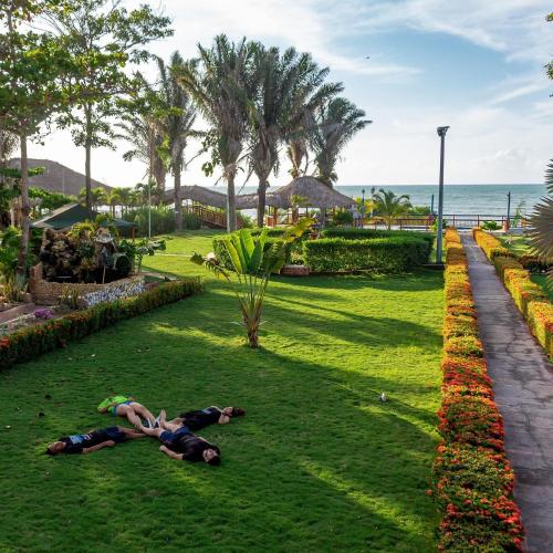 two people laying on the grass near the ocean at Hotel Agroturistico Palma Vino in Arboletes