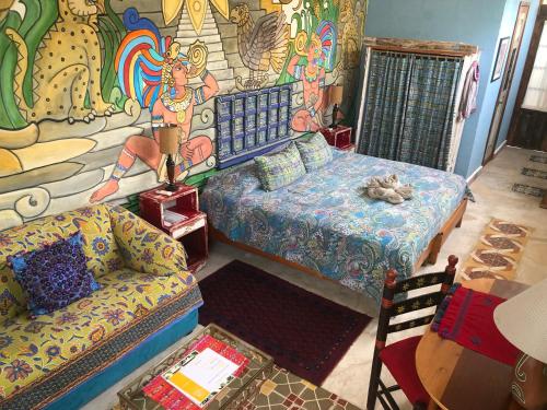 a room with a bed and a couch and a mural at Pueblo Maya by Majikal B&B in Mérida