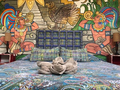 a bed in front of a wall with a mural at Pueblo Maya by Majikal B&B in Mérida