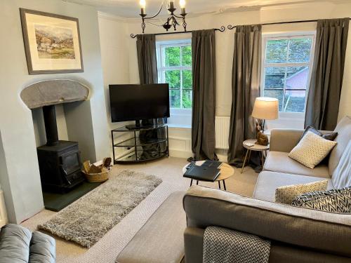 - un salon avec un canapé et une cheminée dans l'établissement Quirky Cottage, Cosy Grade II listed 2 bed apartment Troutbeck Bridge, à Windermere