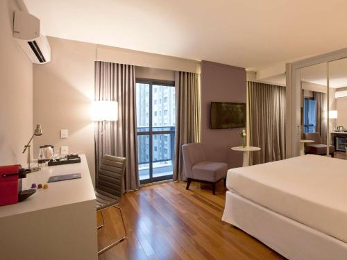 a hotel room with a bed and a desk and a table at NH Collection Curitiba in Curitiba