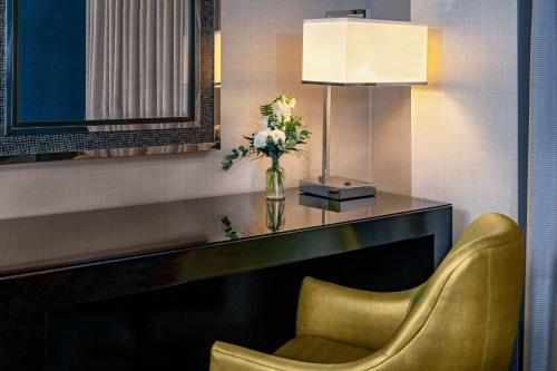 a room with a desk with a chair and a vase of flowers at The Royal Sonesta Boston in Cambridge