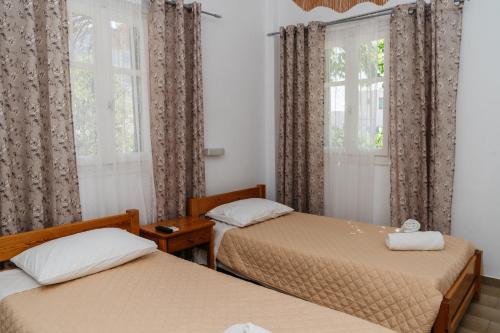 two beds in a room with two windows at Oasis in Kamarai