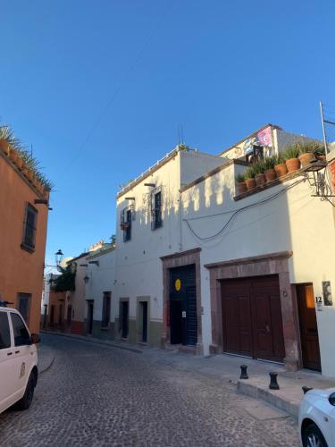a white building with a brown door on a street at Hotel del Sol in San Miguel de Allende