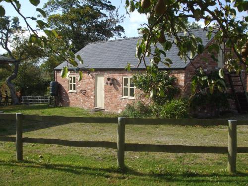 a brick house with a fence in front of it at Little Pentre Barn with cozy logburner in Wrexham