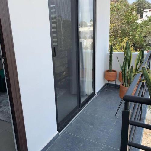 a balcony with a sliding glass door and plants at Playa sur, 5 min playa camina, machado, olas! in Mazatlán