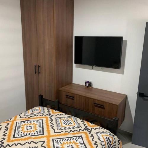 a bedroom with a bed and a flat screen tv at Playa sur, 5 min playa camina, machado, olas! in Mazatlán