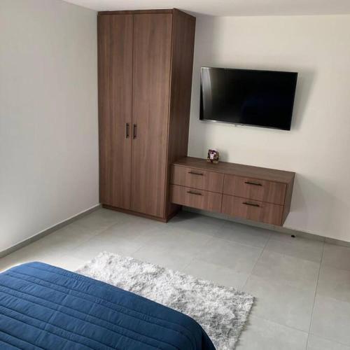 a bedroom with a bed and a flat screen tv at Playa sur, 5 min playa camina, machado, olas! in Mazatlán