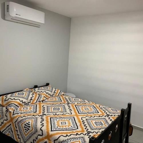 a bed with a quilt on it in a room at Playa sur, 5 min playa camina, machado, olas! in Mazatlán
