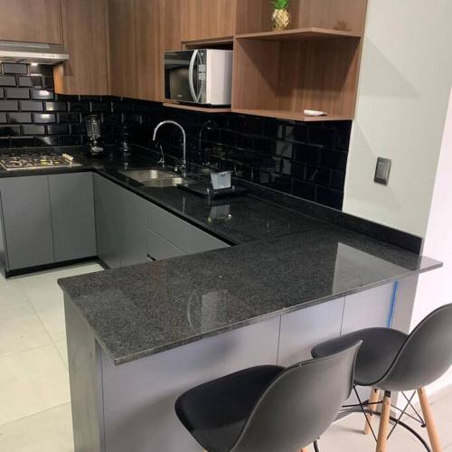 a kitchen with a counter with two chairs and a sink at Playa sur, 5 min playa camina, machado, olas! in Mazatlán