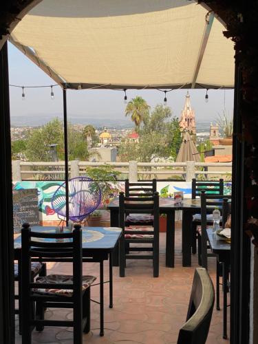 um pátio exterior com mesas, cadeiras e um guarda-sol em Hotel del Sol em San Miguel de Allende