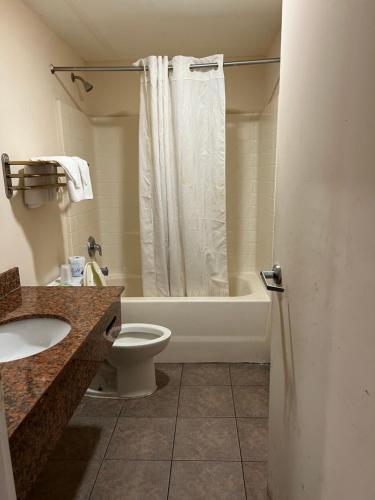 a bathroom with a tub and a toilet and a sink at Metro Inn & Suites in Jacksonville