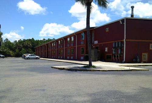 a red building with a palm tree next to a parking lot at Metro Inn & Suites in Jacksonville