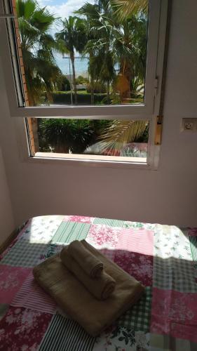 a bed with a towel on it with a window at HABITACIONES EN frente DEL PUERTO in Almería
