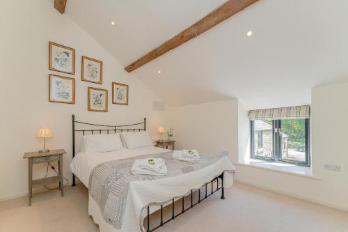 a white bedroom with a bed and a window at The Hayloft in Mold