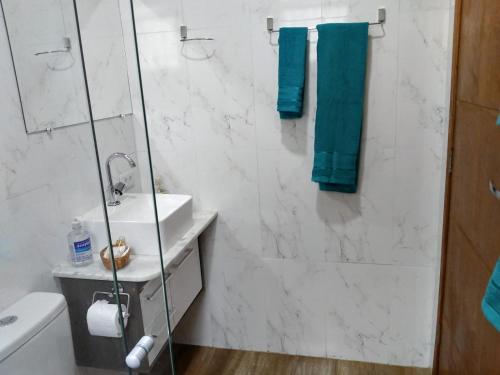 a bathroom with a sink and a shower with blue towels at Cantinho da Divina Paz in São Bento do Sapucaí
