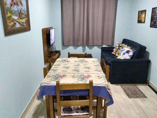 a dining room with a table and a couch at Cantinho da Divina Paz in São Bento do Sapucaí