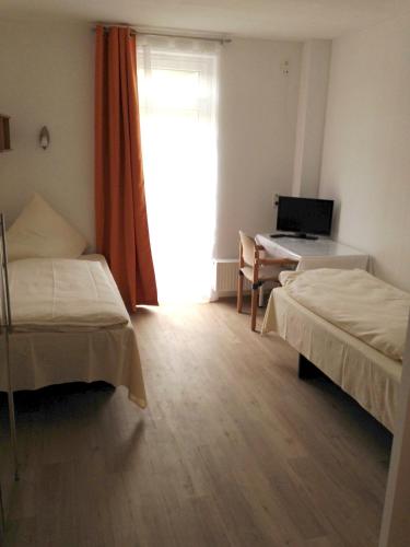 a room with two beds and a desk with a laptop at i-Motel in Obertshausen