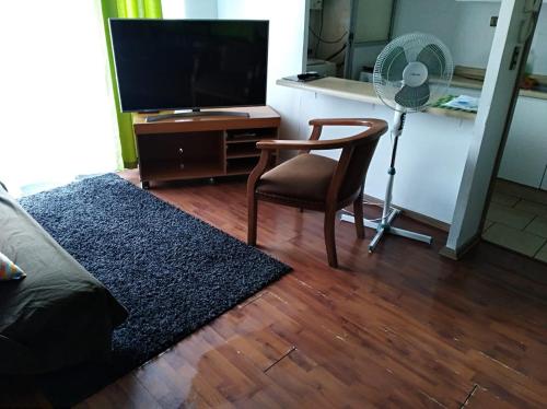 a living room with a tv and a chair and a fan at Departamento Hospedaje Rancagua Centro in Rancagua