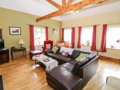 a living room with a leather couch and red curtains at Prague House in Lettermore