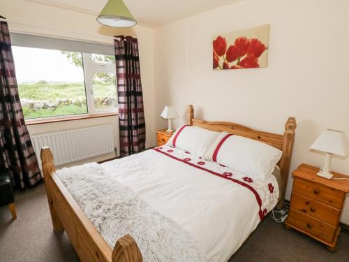 - une chambre avec un grand lit et une fenêtre dans l'établissement Roundstone Bay View, à Roundstone
