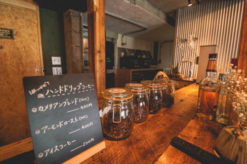 un grupo de tarros sobre una mesa de madera con una señal en Camellia Complex, en Inawashiro